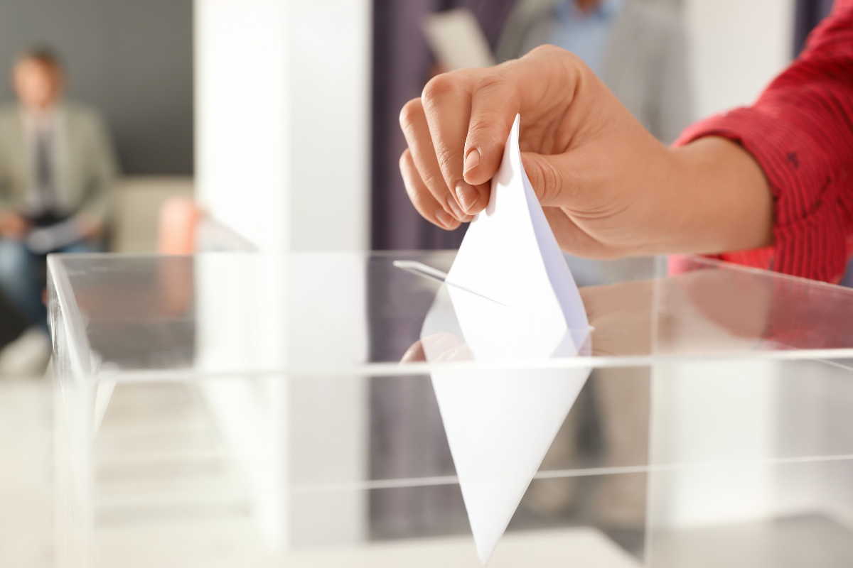 Stimmzettel wird in Urne eingeworfen