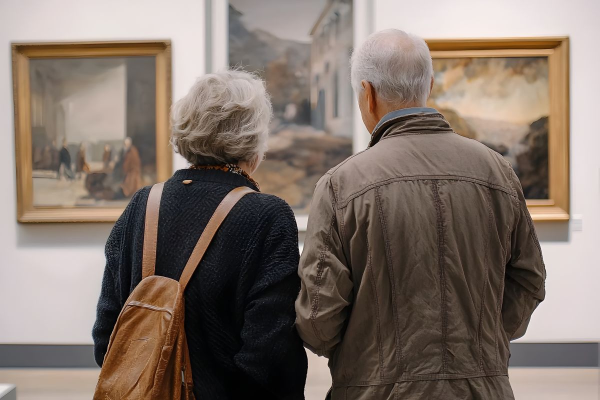 Ein älteres Paar betrachtet Gemälde in einer Galerie.