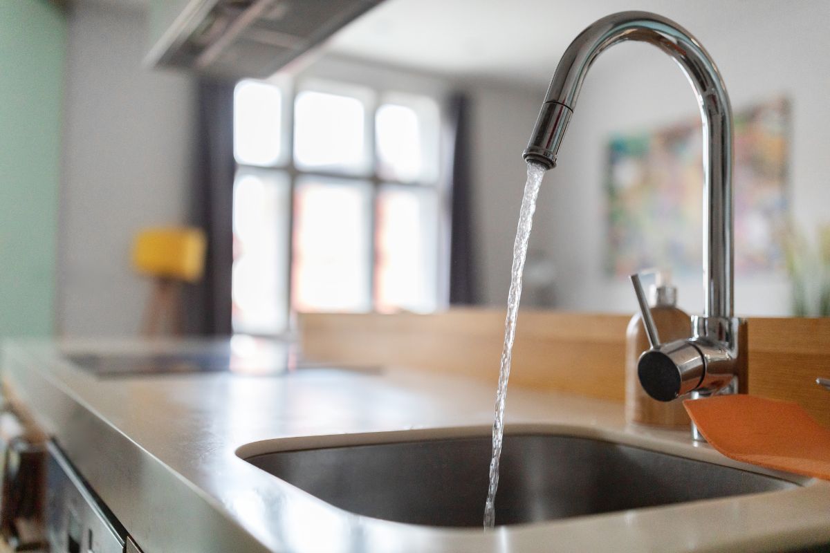 Wasserverbrauch Wasser fließt aus einem Hahn in der Küche