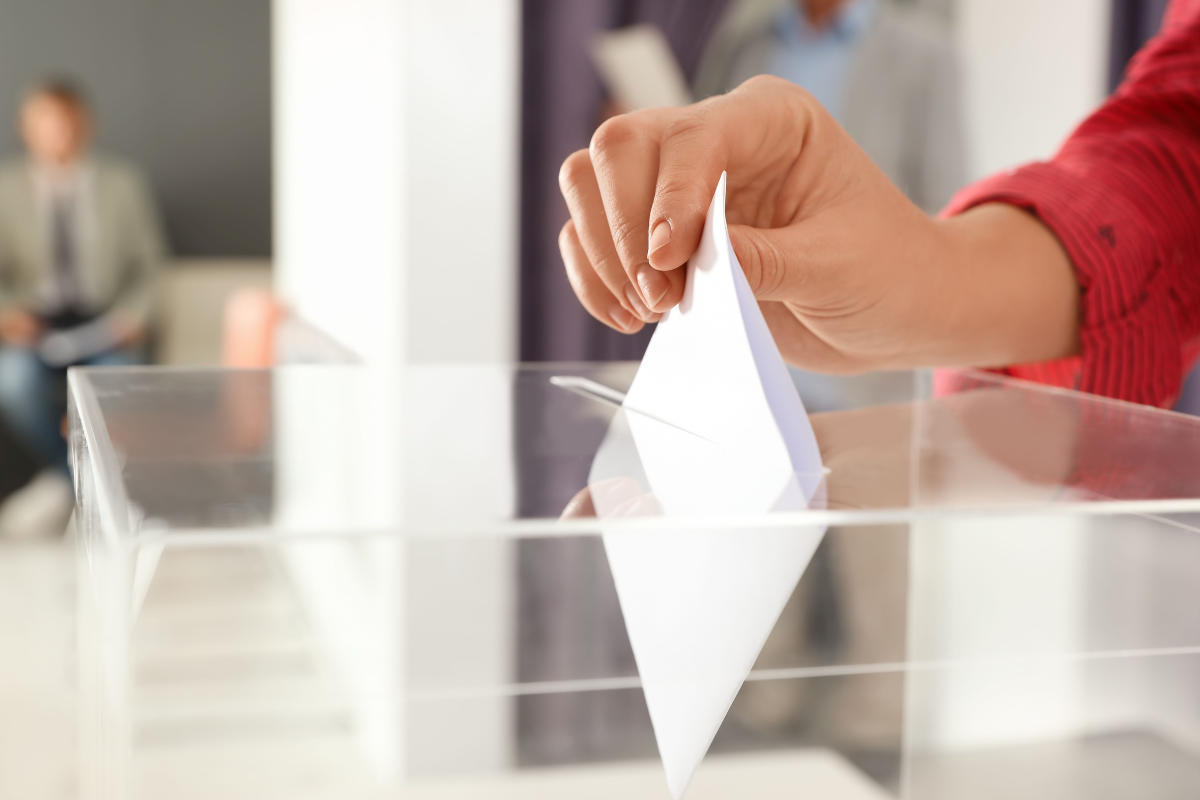 Stimmzettel wird in Wahlurne gesteckt