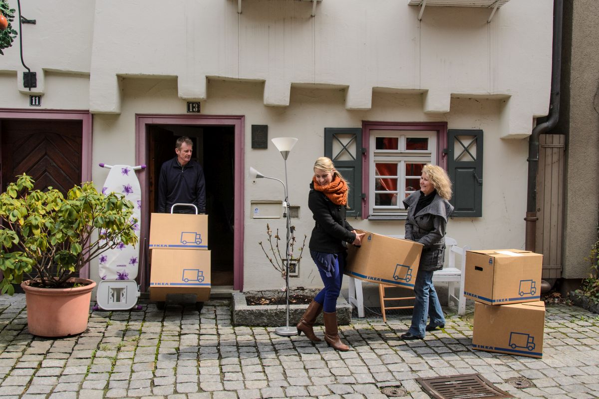 Personen bringen Umzugskisten in ein Altstadthaus.