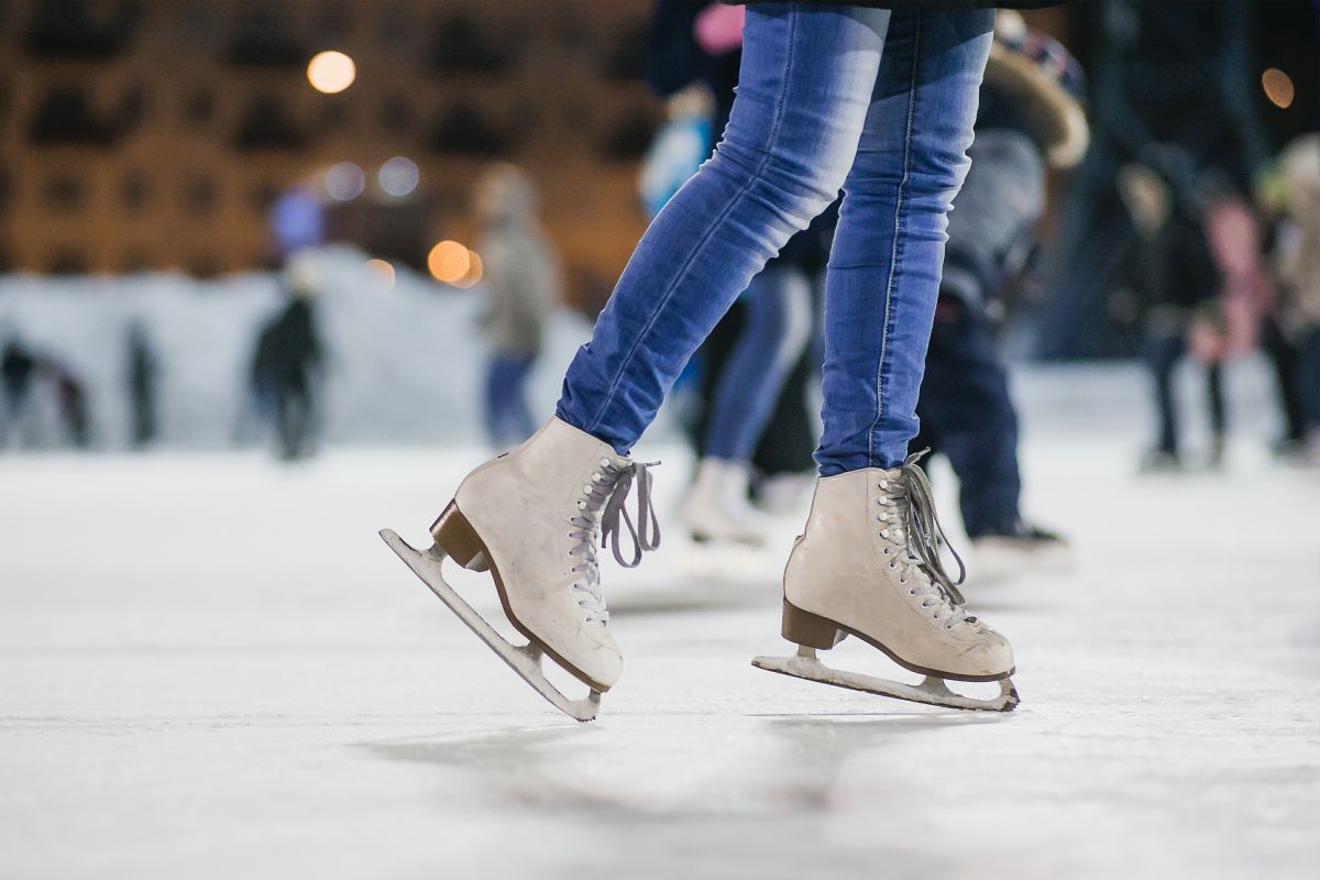 Eisbahn, Frau mit Jeans und weißen Schlittschuhen.