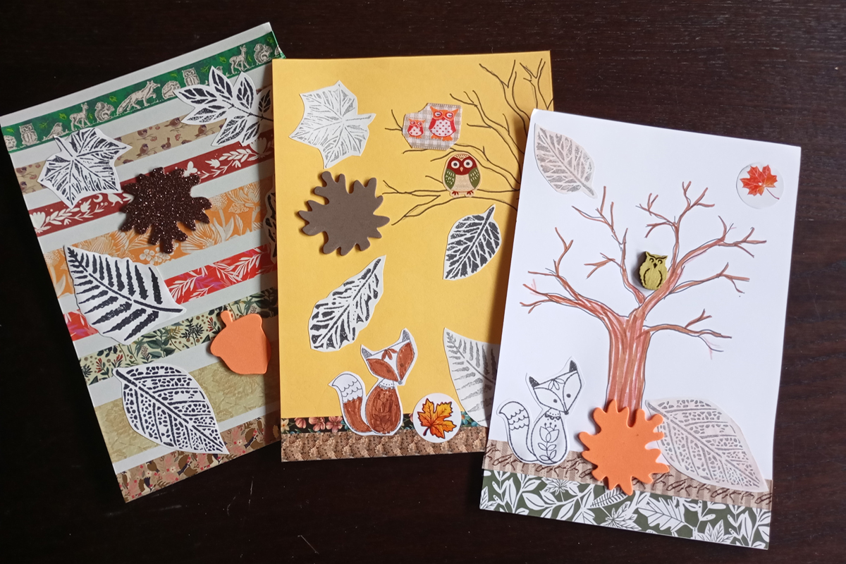 Drei Karten mit ausgestanzten und bemalten Papiermotiven gestaltet sind. Es sind Tiere und Herbst-Motive wie fallende und fliegende Blätter und kahle Bäume.