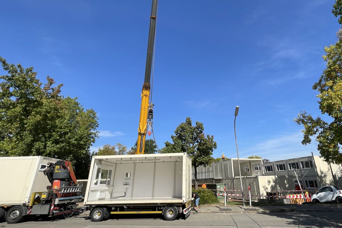 Die Container werden mit einem Kran auf Tieflader verladen.