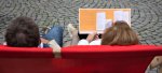 Ein Paar liest das Programmheft des Glockenspiel-Festivals in einem roten Liegestuhl