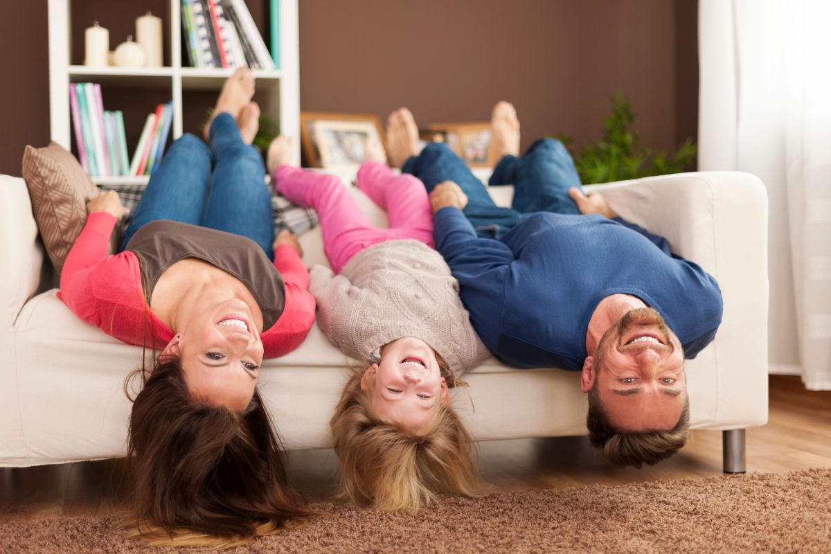 Vater, Mutter und Kind toben auf dem Sofa.