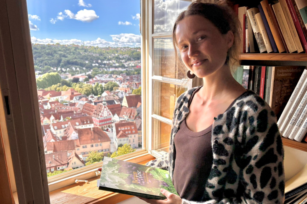 Elfa D'Avis Elfa D'Avis steht am Fenster in der Hochwacht, mit einem Buch in der Hand.