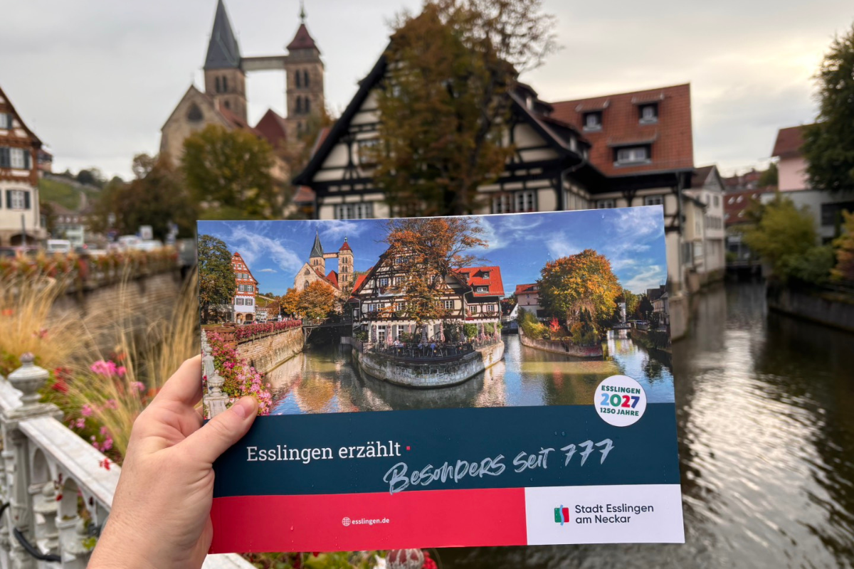 ES erzählt Broschüre wird an der agnesbrücke ins Bild gehalten, gleiches Motiv wie auf dem Titelfoto.