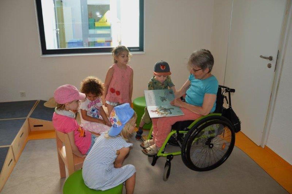 Kinder lauschen gebannt einer Frau beim Vorlesen.