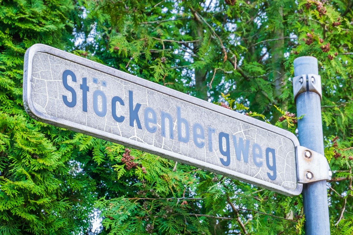 Straßenschild des Stöckenbergwegs vor grünen Blättern