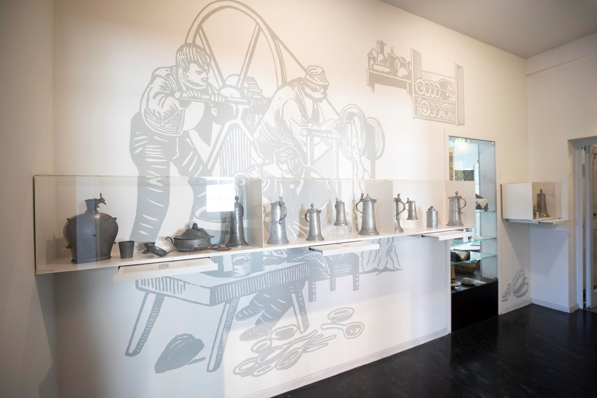 Stadtmuseum Esslingen_Zinnraum01 ©Städtische Museen Esslingen, Michael Saile Blick in einen Raum, in dem Zinngefäße in Glasschaukästen an der Wand präsentiert werden