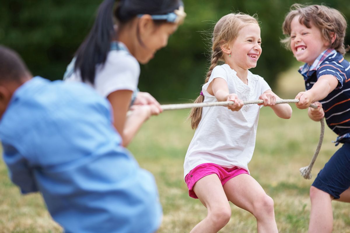 Kinder beim Tauziehen auf einer Wiese.