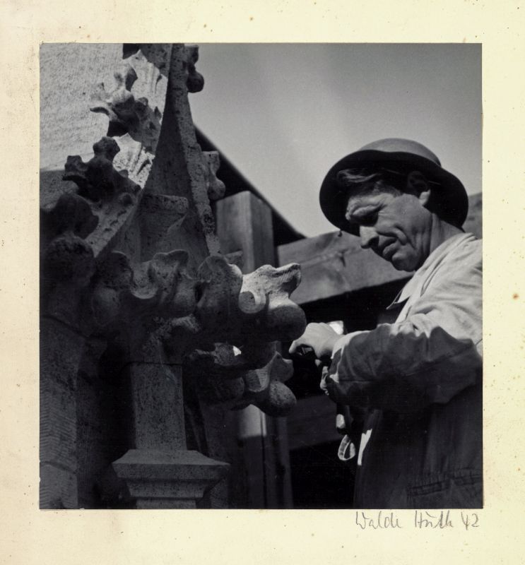 Ein Mann arbeitet mit Hammer und Meißel an einer gotischen Steinverzierung 